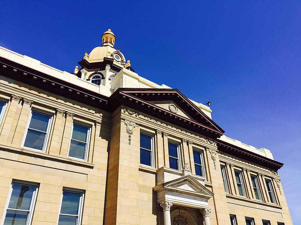 Front entrance of the historic Pierce County Courthouse in Ellsworth, featuring its distinctive copper-colored dome under a clear blue sky., Pierce County, Wisconsin